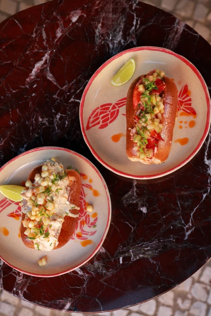 Lobster brioche rolls on Pinch plates on a marble table in Lisbon, one with lobster and diced pepper