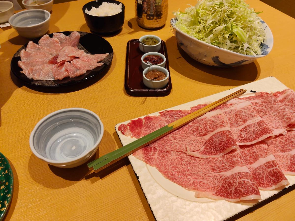 新宿のしゃぶしゃぶの食卓。薄切り肉とキャベツ、薬味の器