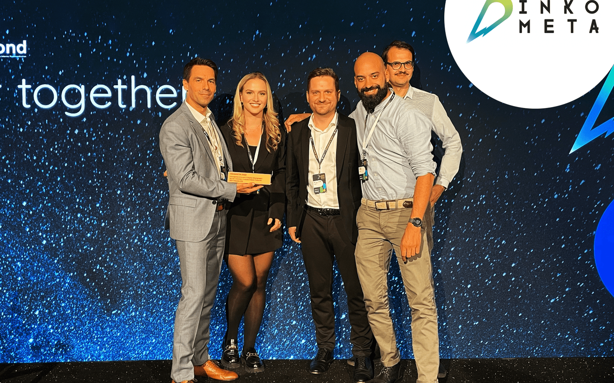 Fünf Personen in Business-Kleidung halten einen Inkometa-Award vor einer blauen Event-Bühne mit Inkometa-Logo.
