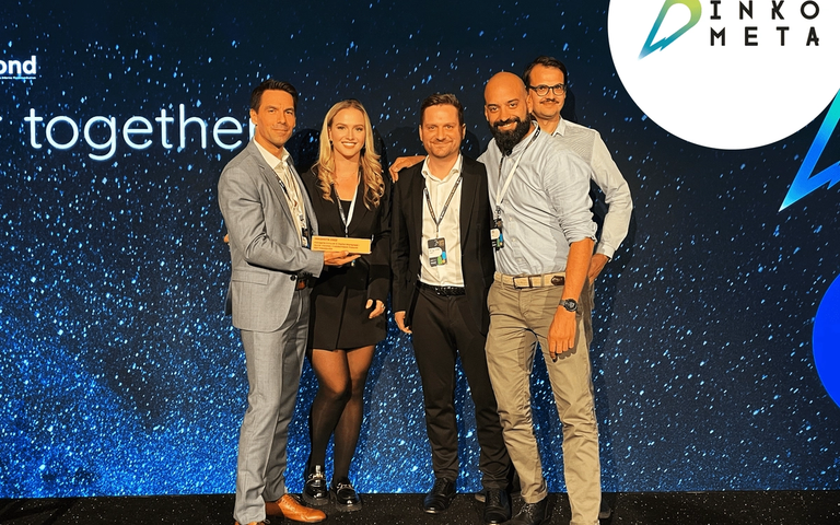 Fünf Personen in Business-Kleidung halten einen Inkometa-Award vor einer blauen Event-Bühne mit Inkometa-Logo.