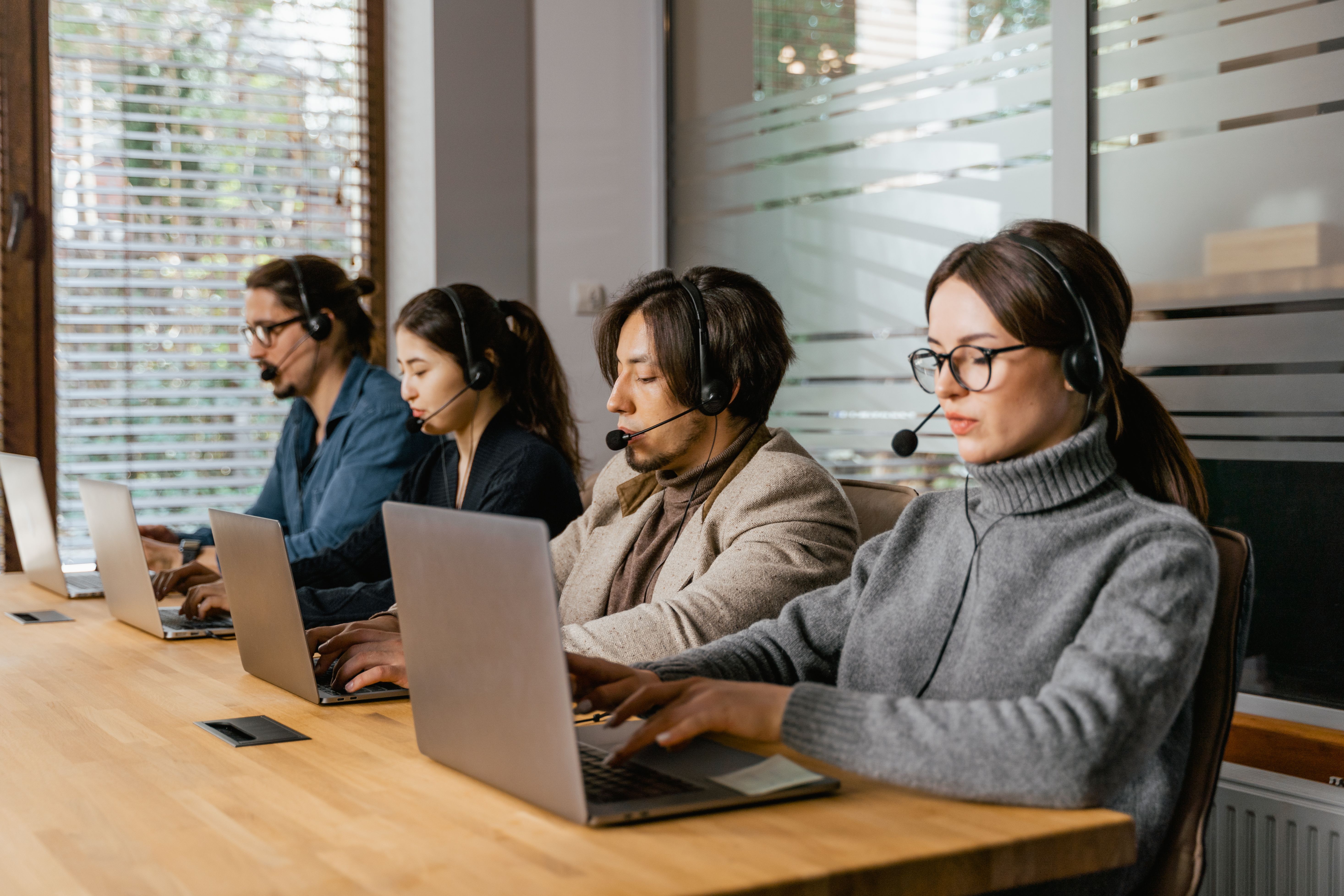Ein Service-Team arbeitet mit Laptops und Headsets in einem modernen Büro