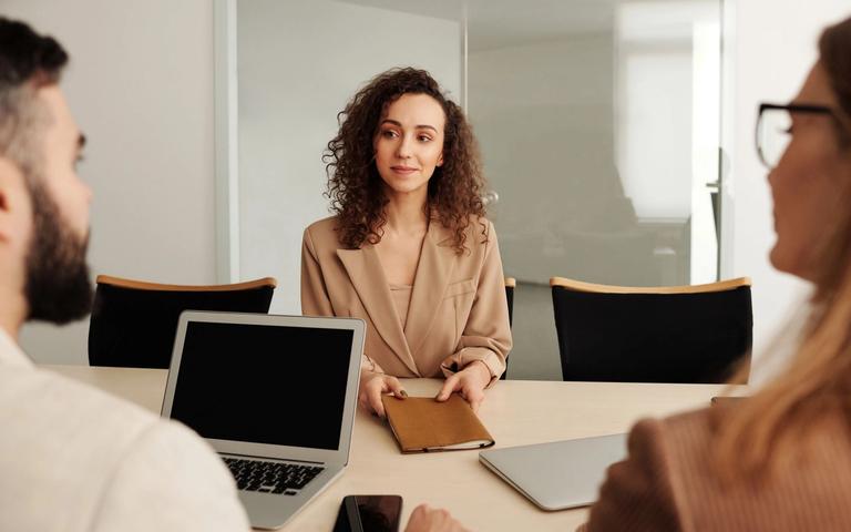 Job candidate in an interview, seated across a meeting table from two people