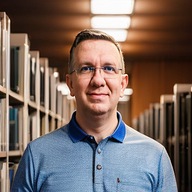 Porträt von Martin Runge mit Brille und blauem Hemd.