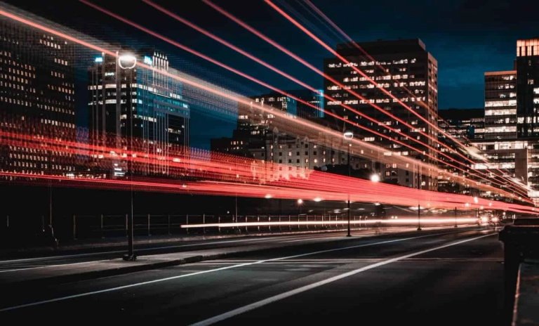 Nächtliche Langzeitbelichtung einer Stadtstraße mit Lichtspuren vor beleuchteten Hochhäusern