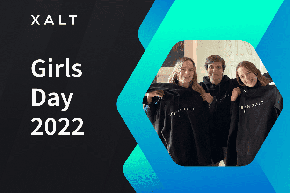 XALT Girls Day 2022 — drei junge Frauen halten schwarze XALT-Hoodies in einem Hexagon-Rahmen auf blauem Hintergrund.