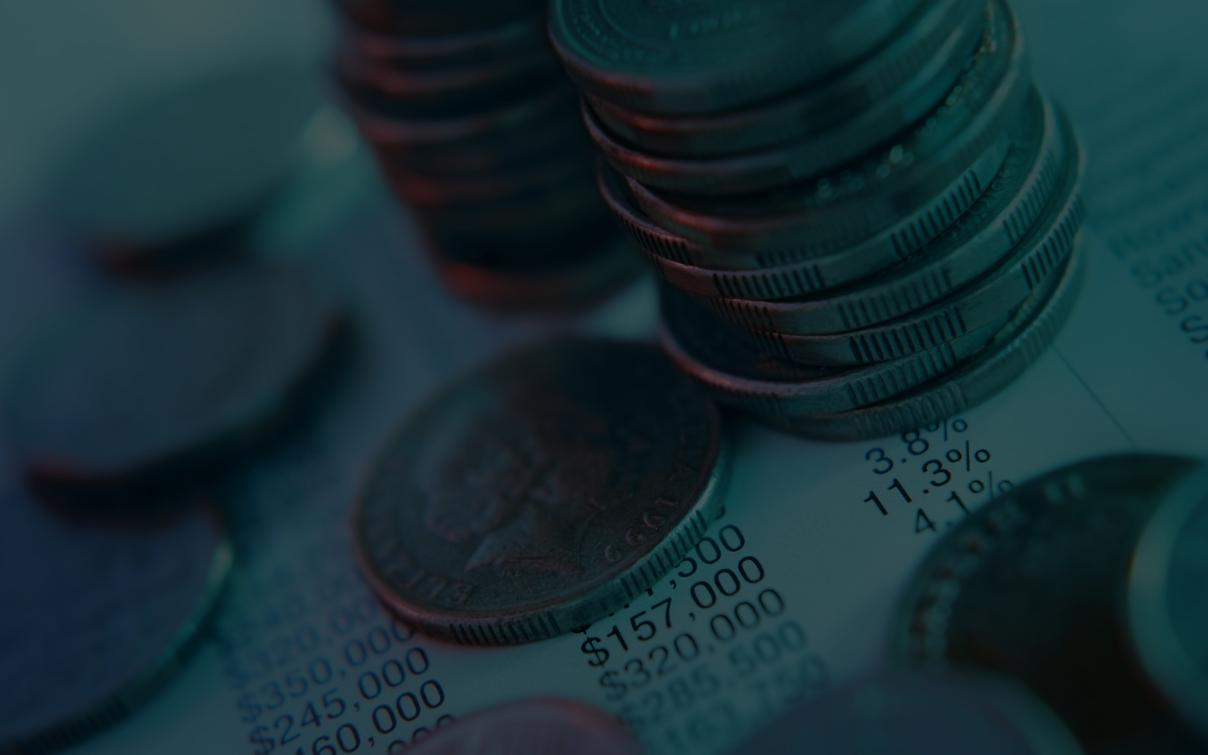 Münzstapel auf Finanzdokument mit Zahlen und Prozentangaben — Symbol für Kosten bei Cloud-Migration.