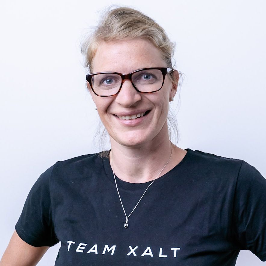 Helen Joas lächelt mit Brille in die Kamera und trägt ein schwarzes TEAM-XALT-Shirt