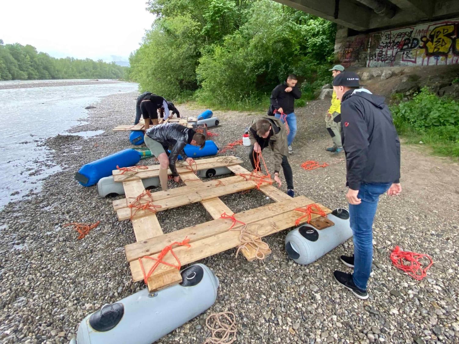 Team-Building beim Bau eines Holzfloßes am Fluss