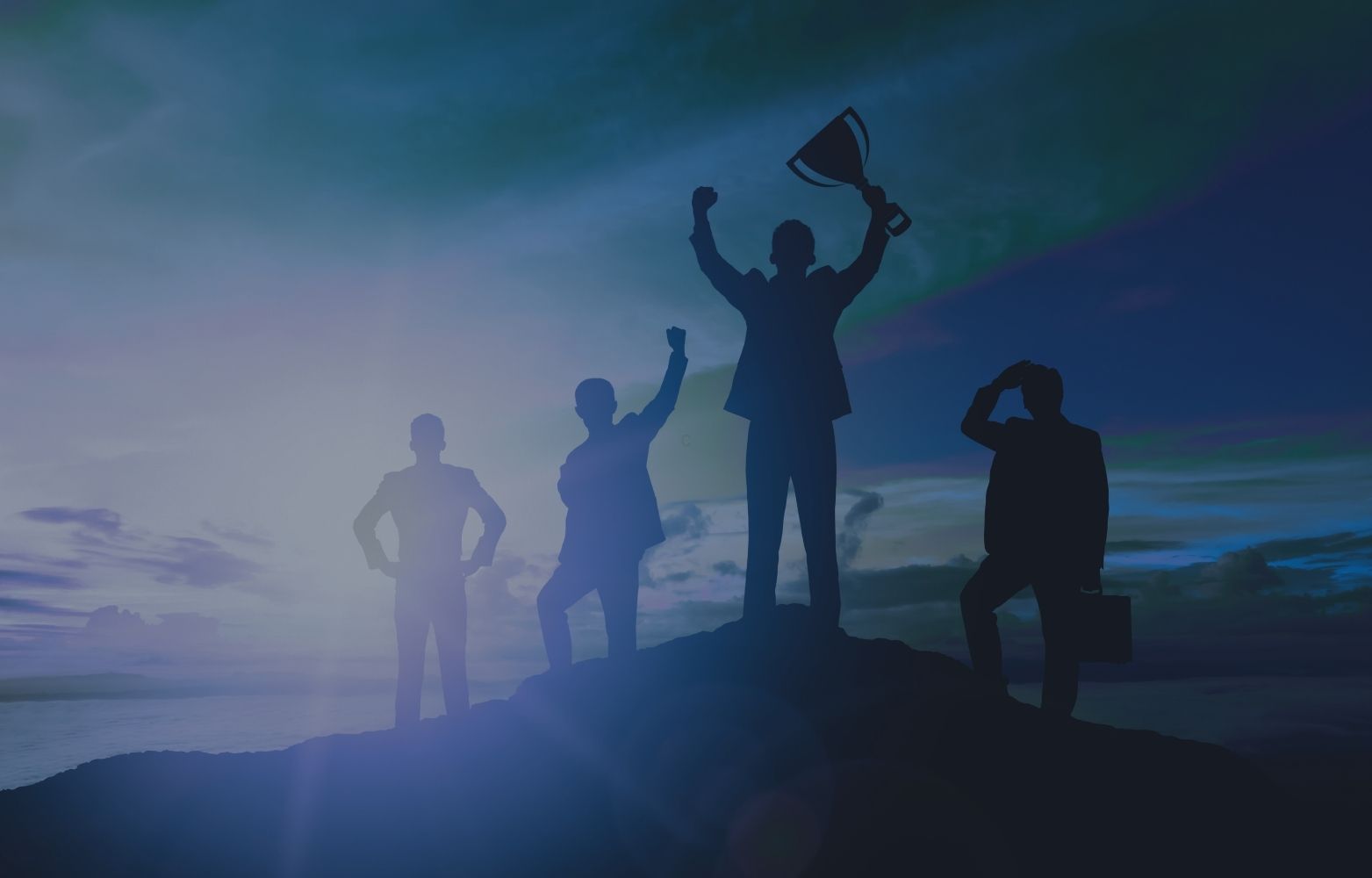 Silhouetten von vier Geschäftsleuten auf einem Berggipfel, einer hält einen Pokal in die Höhe vor blauem Himmel.