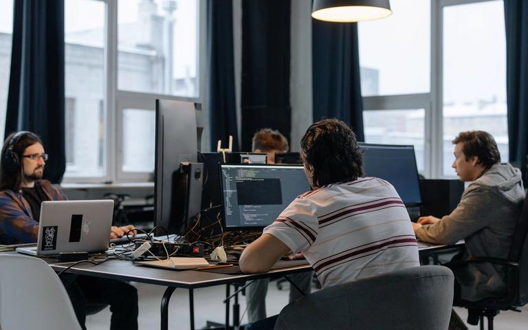 Development team working at desks with monitors and laptops in a bright loft office