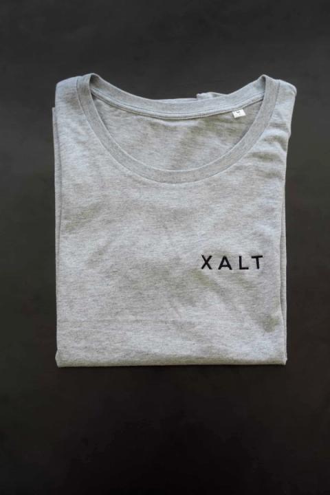 Ein hellgraues T-Shirt mit schwarzem XALT-Schriftzug auf der Brust