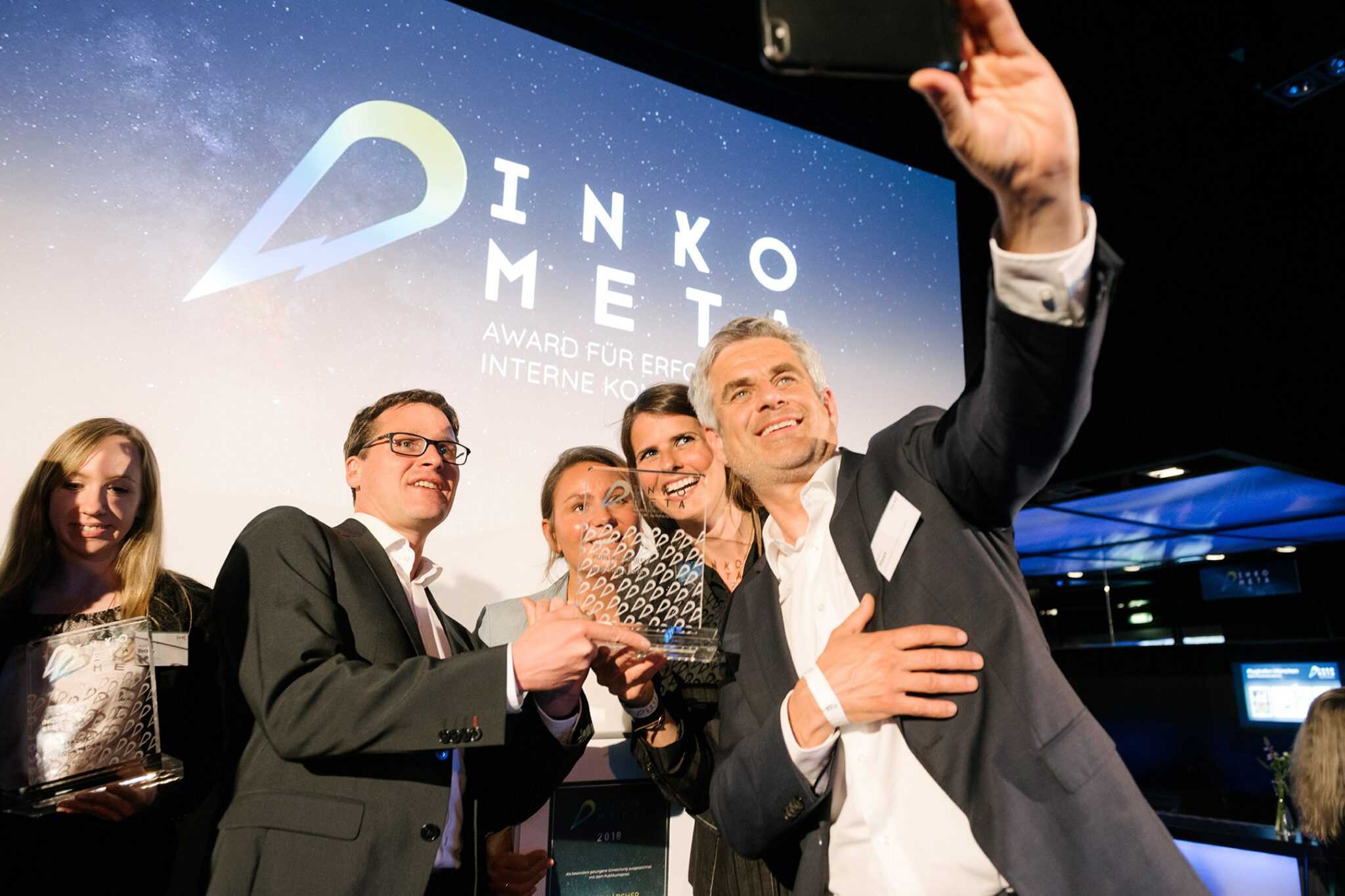 XALT-Team bei der DINKOMETA Award-Verleihung mit Trophäe, Hintergrund: DINKOMETA Logo und Award-Banner.