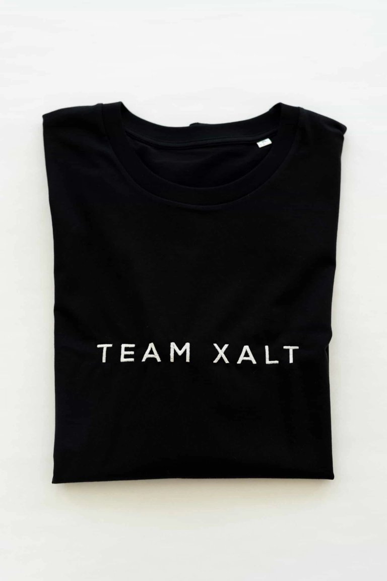 Ein gefaltetes schwarzes T-Shirt mit weißem TEAM-XALT-Schriftzug