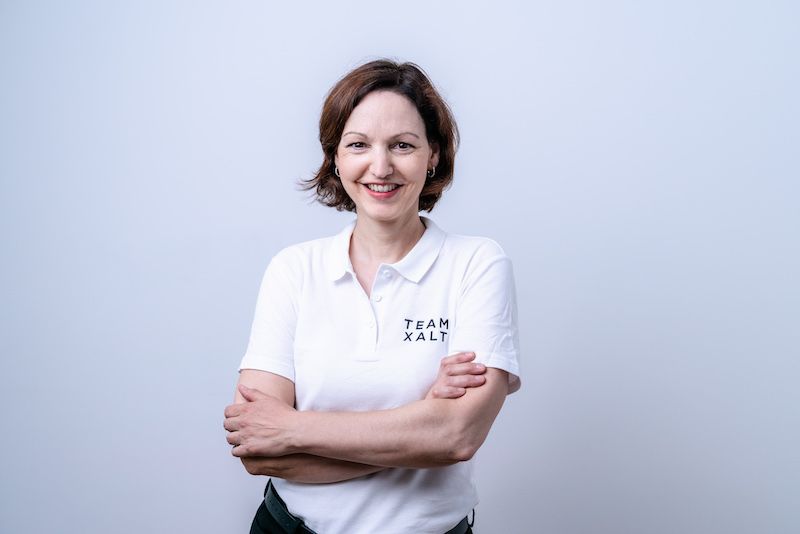Susanne smiles at the camera with her arms crossed, wearing a white polo shirt