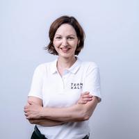 Susanne smiles at the camera with her arms crossed, wearing a white polo shirt