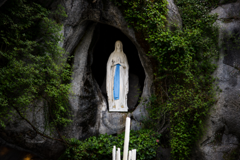Imagen de la Virgen de Lourdes en la gruta, rodeada de vegetación