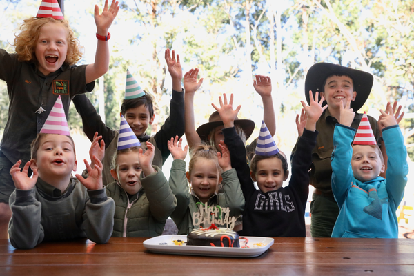 Children celebrating a birthday in front of cake