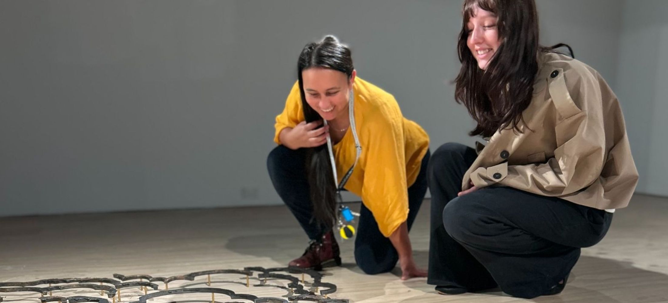 A young person and an Art Facilitator discuss a sculptural artwork on the ground