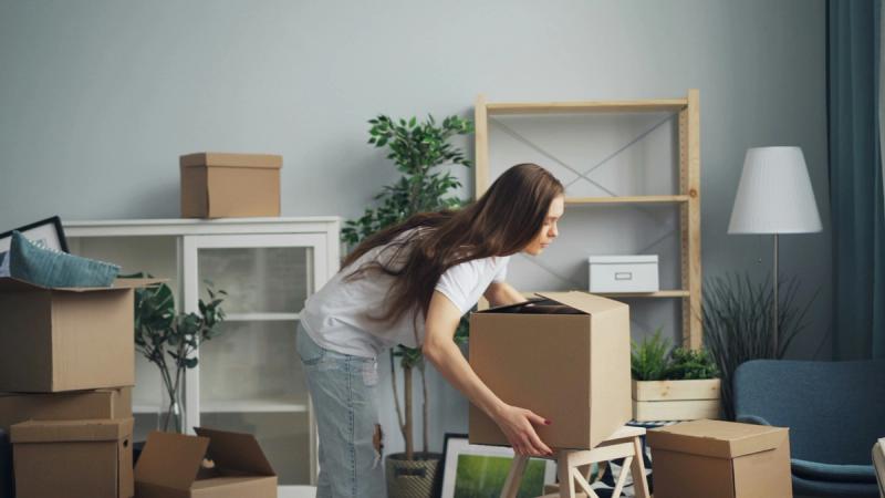 Girl moving home with packed boxes 