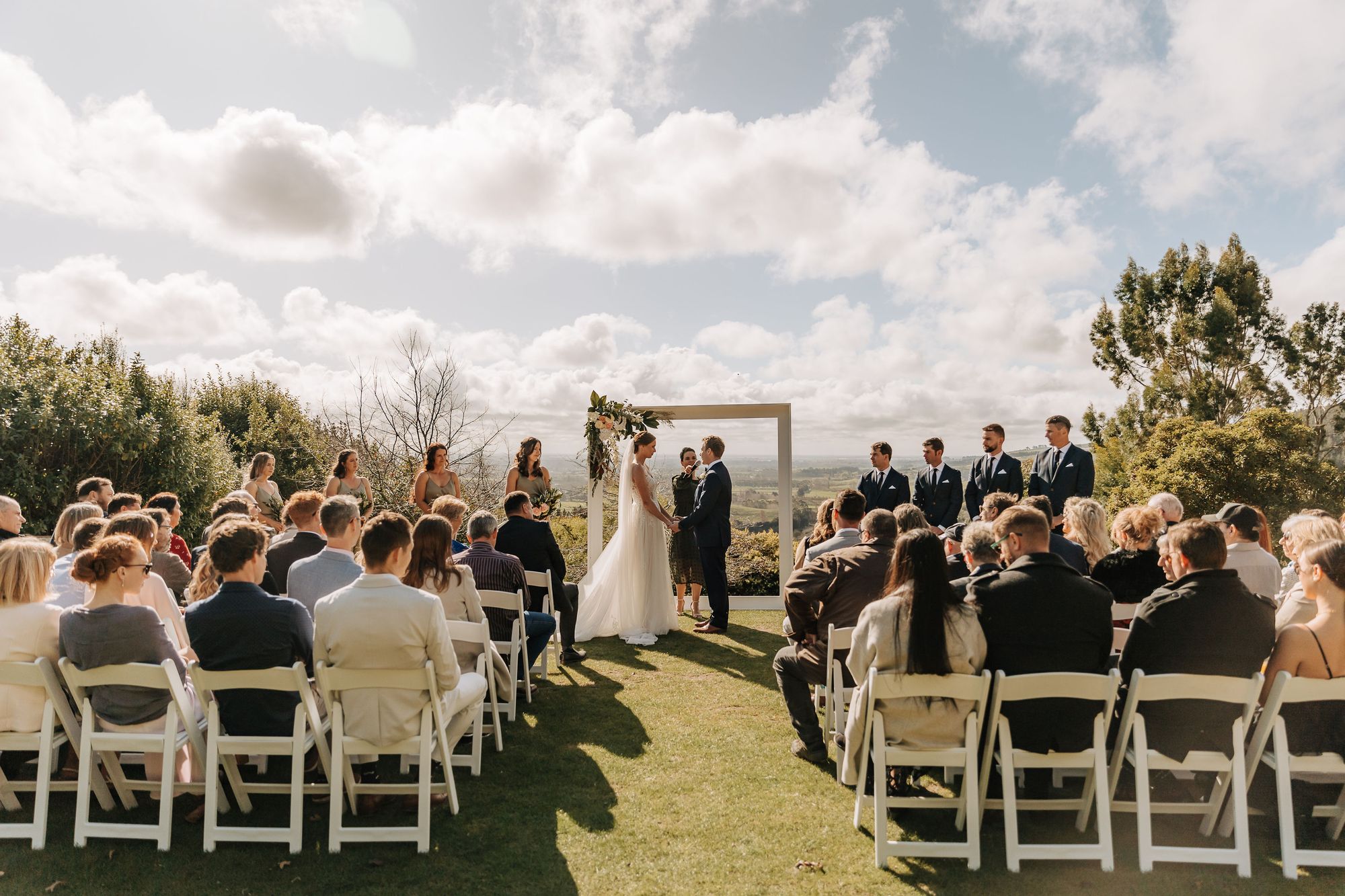 Outdoor wedding ceremony at Waipuna Estate overlooking rolling green hills