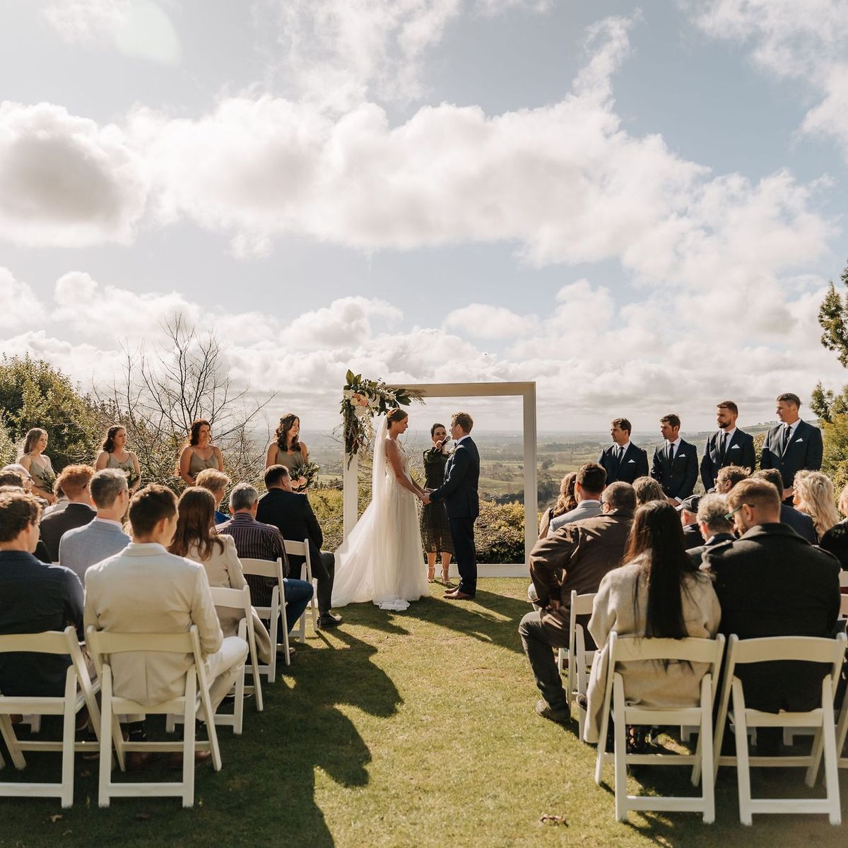 Outdoor wedding ceremony at Waipuna Estate overlooking rolling green hills