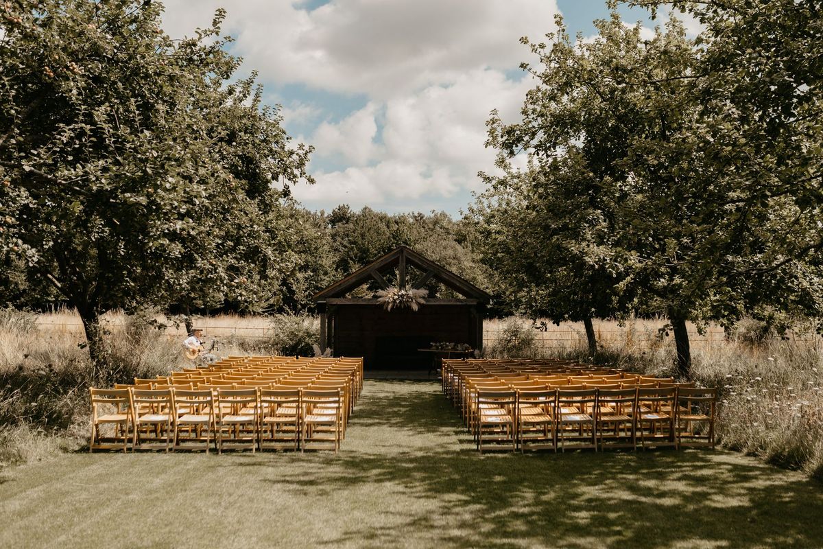 Outdoor wedding ceremony aisle among orchard trees at Chapel House Estate
