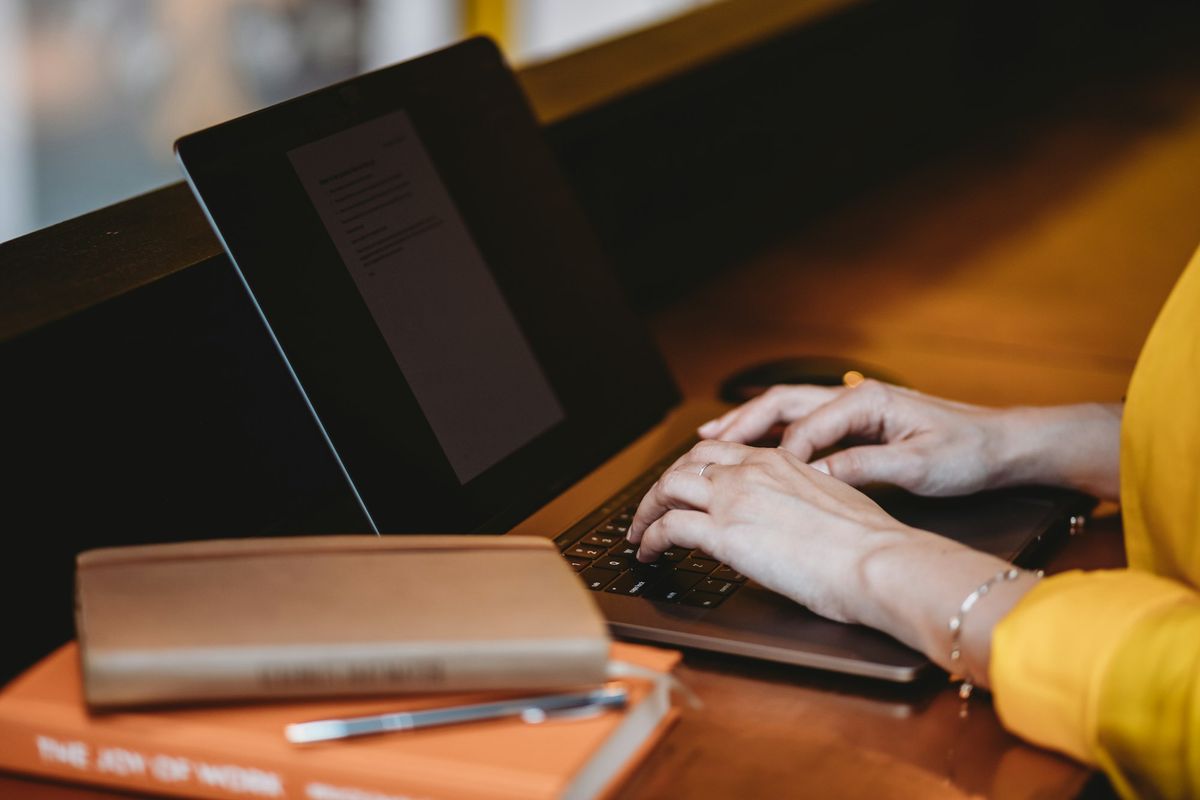 A freelancer working on a MacBook Pro beside two notebooks