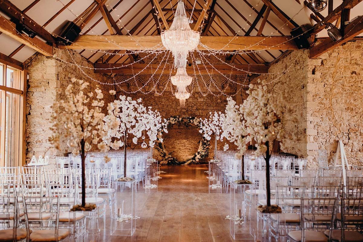 Candlelit barn wedding aisle at Harper Weddings lined with blossom trees and a chandelier