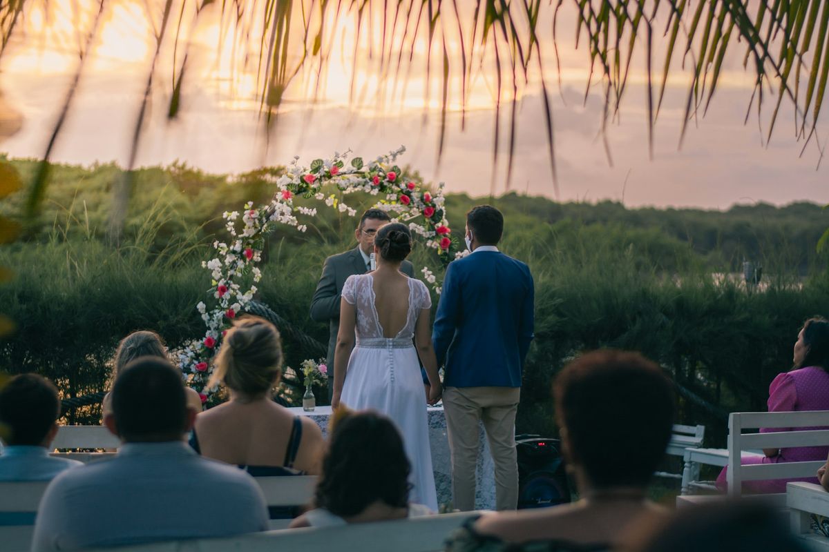 Outdoor wedding ceremony at sunset with a floral arch overlooking the sea