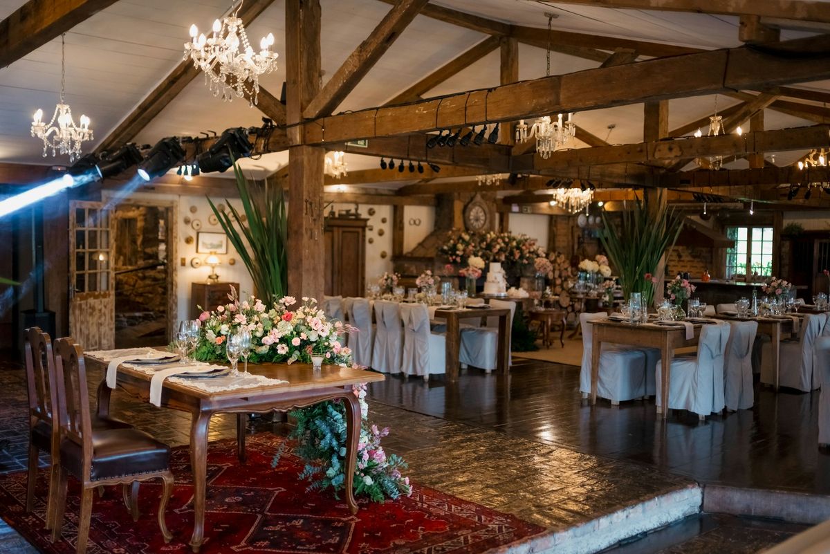 Elegant event hall decorated with flowers and wooden beams.
