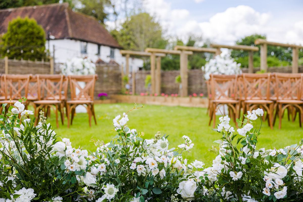 Outdoor ceremony setup with wooden chairs and a pergola at The Orchard