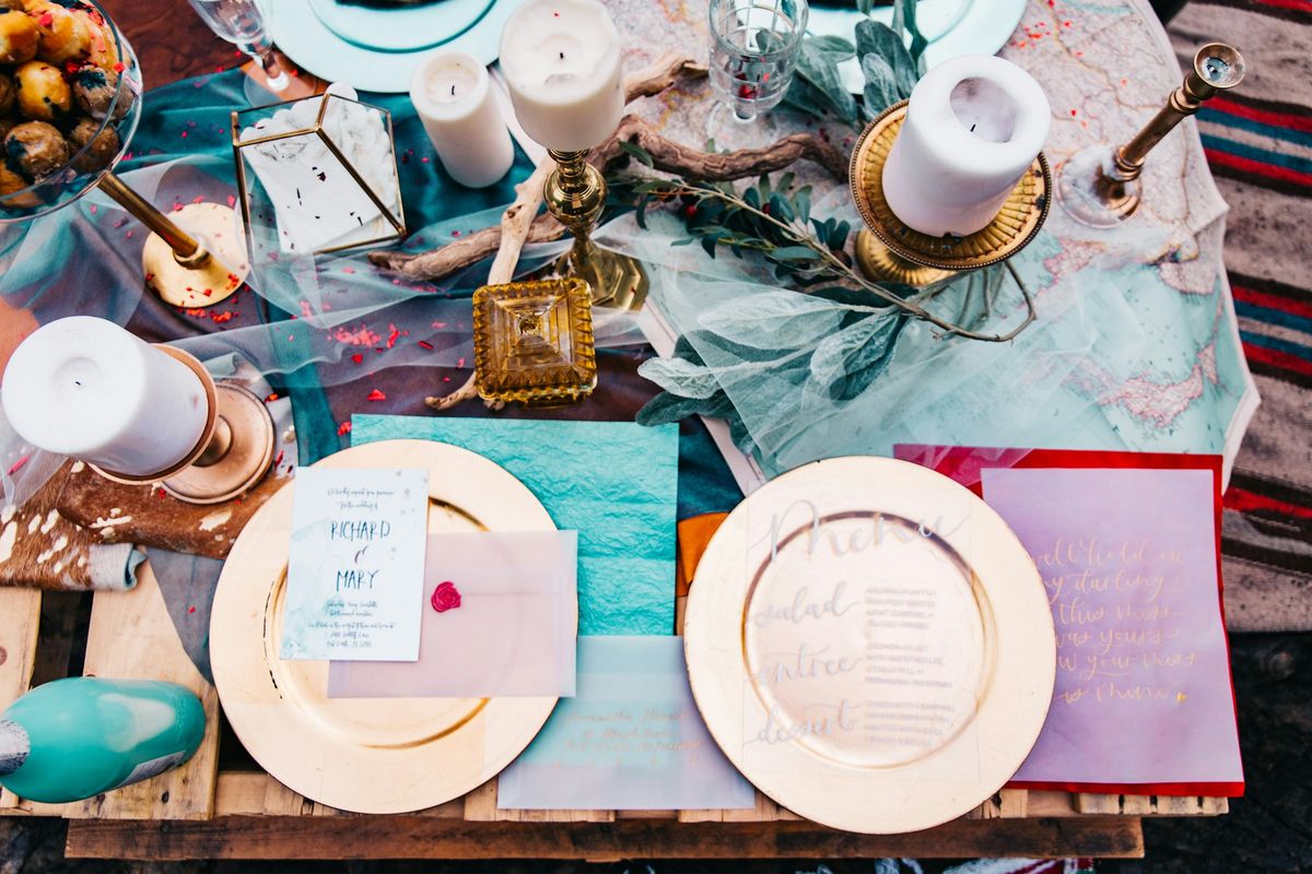 Eclectic styled wedding table setting with gold-rimmed plates and candles