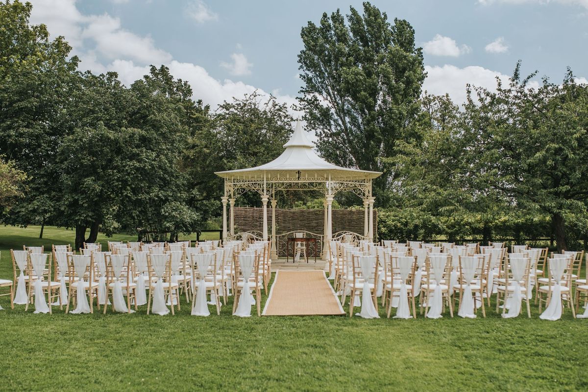 Outdoor wedding ceremony with a white pavilion and draped chairs at a Tabor Group venue