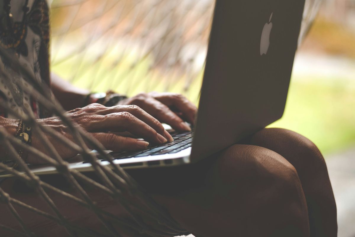 A person typing on a laptop outdoors