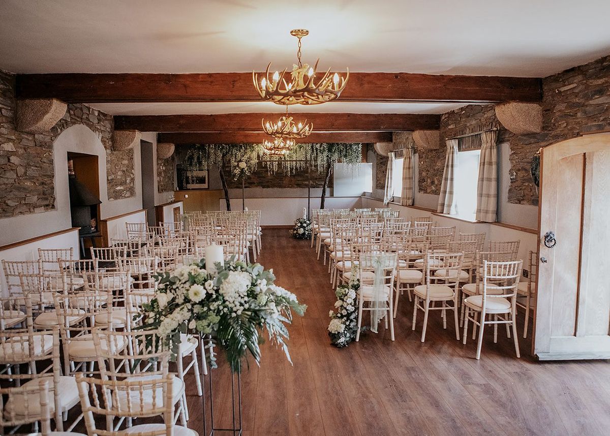 Stone-walled ceremony room at Wooladon Estate with antler chandeliers and chiavari chairs