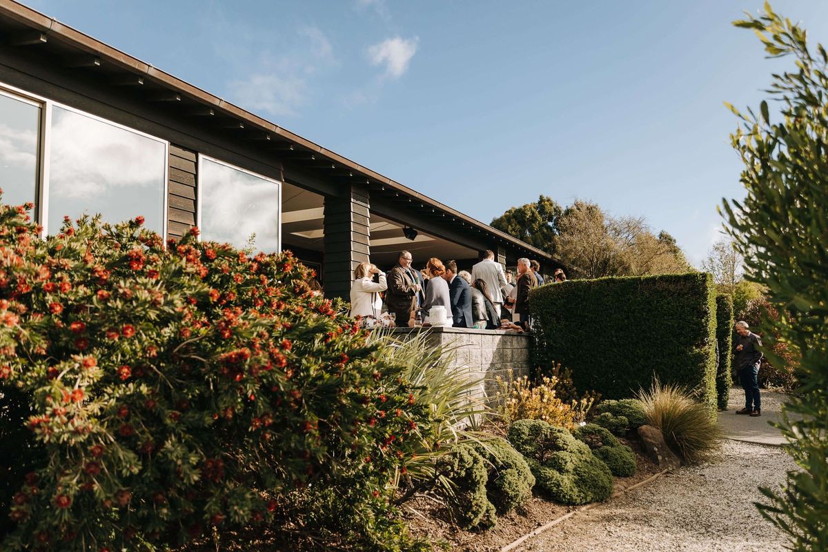 Guests mingling on the terrace at Waipuna Estate among flowering shrubs