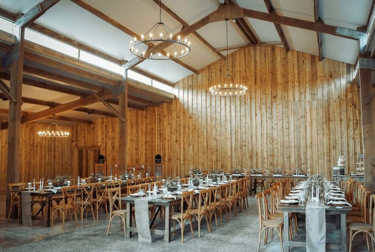 Timber-clad barn reception at Wooladon Estate with long tables and ring chandeliers