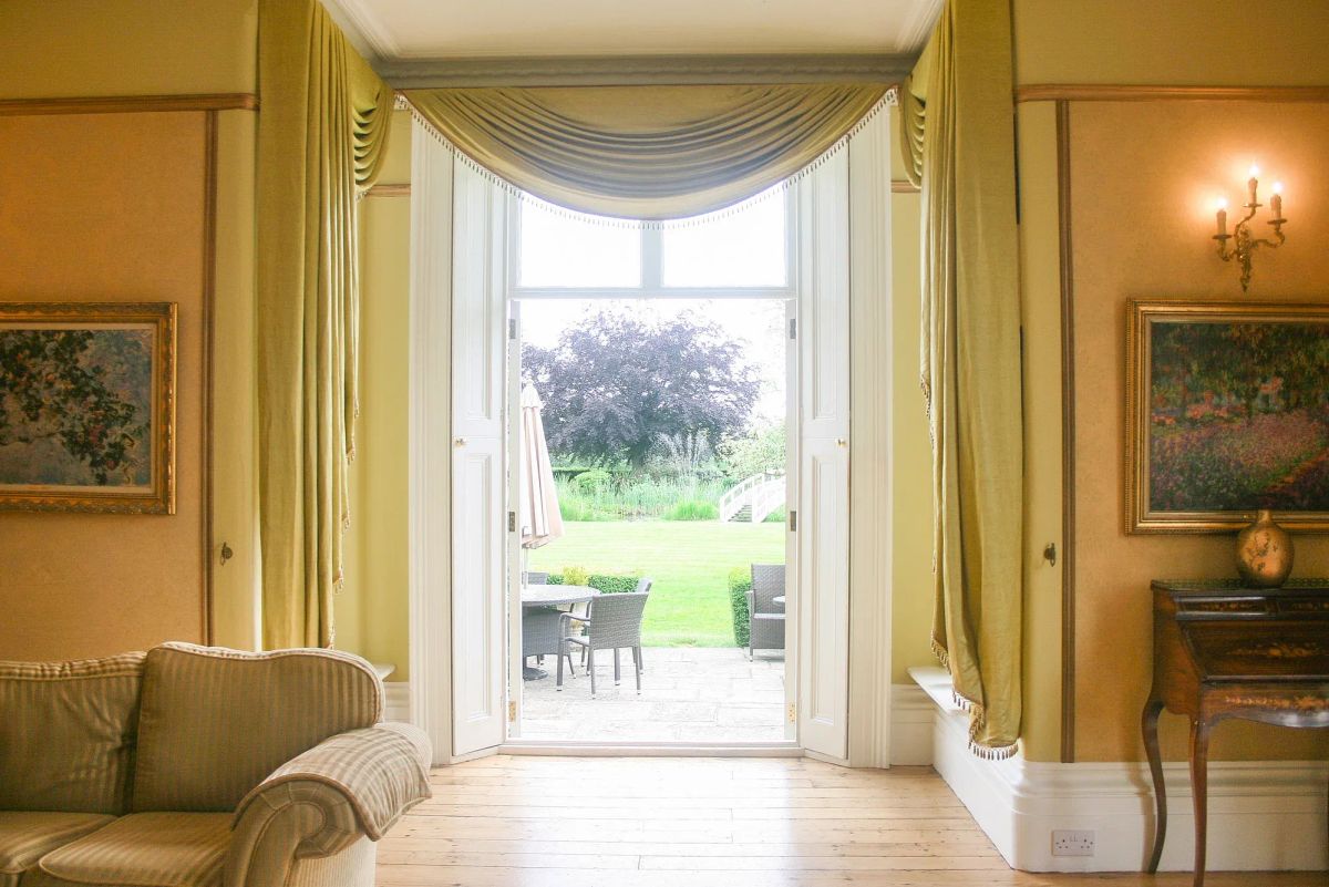 Yellow-curtained lounge at a Tabor Group venue opening onto the garden terrace