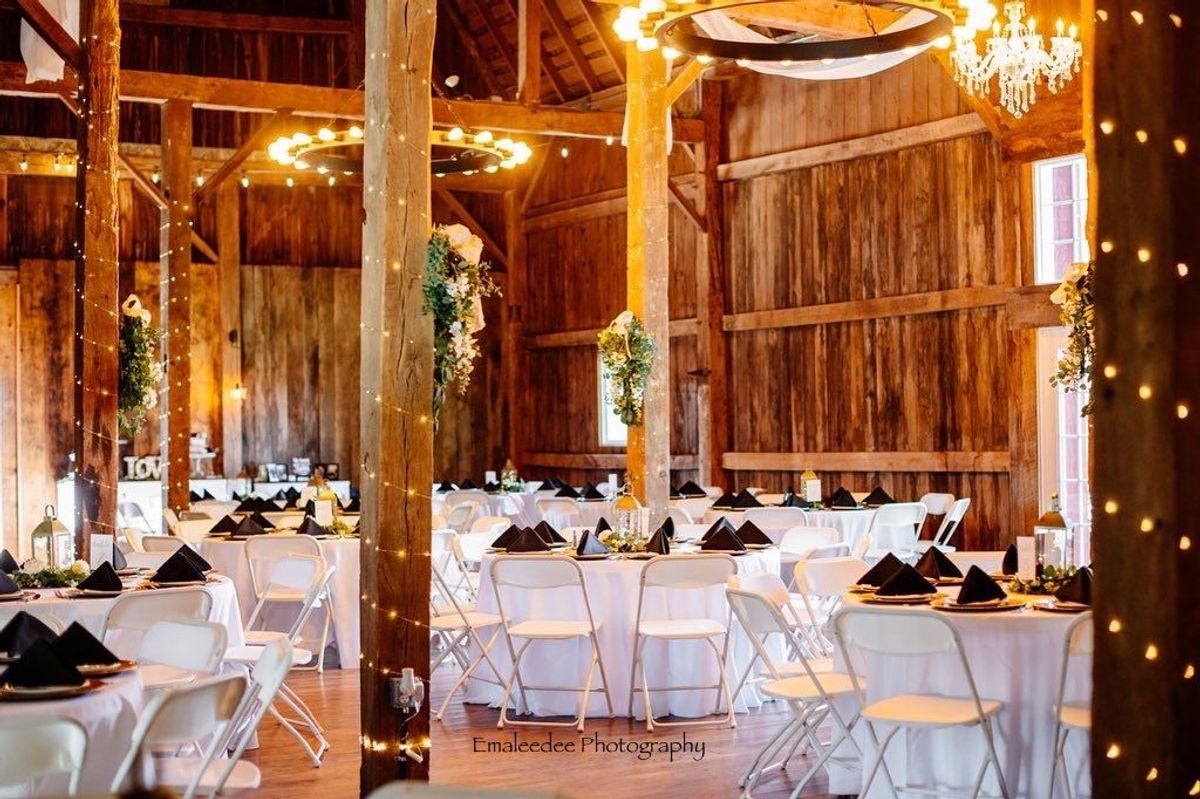 Rustic barn reception at Barn 1888 with fairy lights and round tables set for dinner