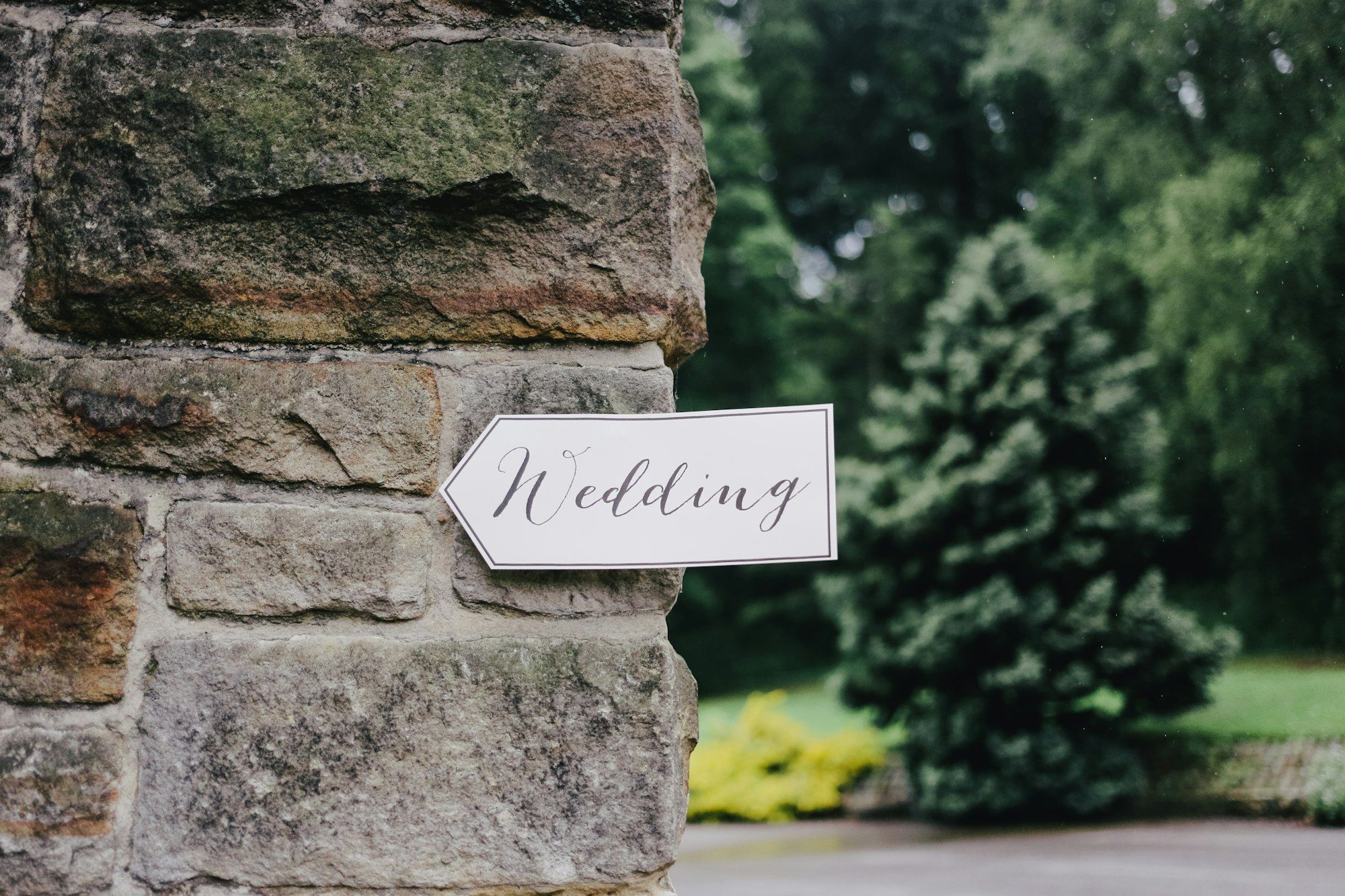 Wooden wedding directional sign fixed to a stone gatepost