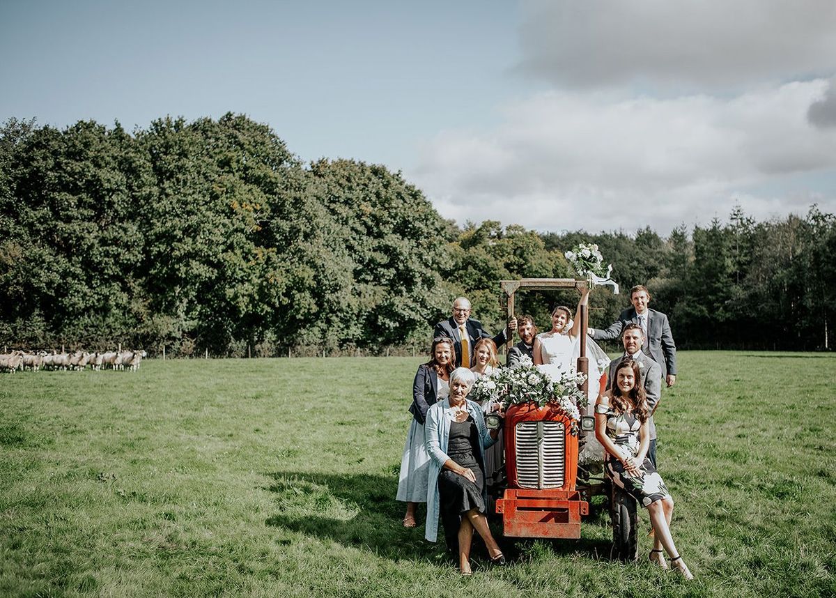 Wedding party gathered around a vintage tractor in the fields at Wooladon Estate