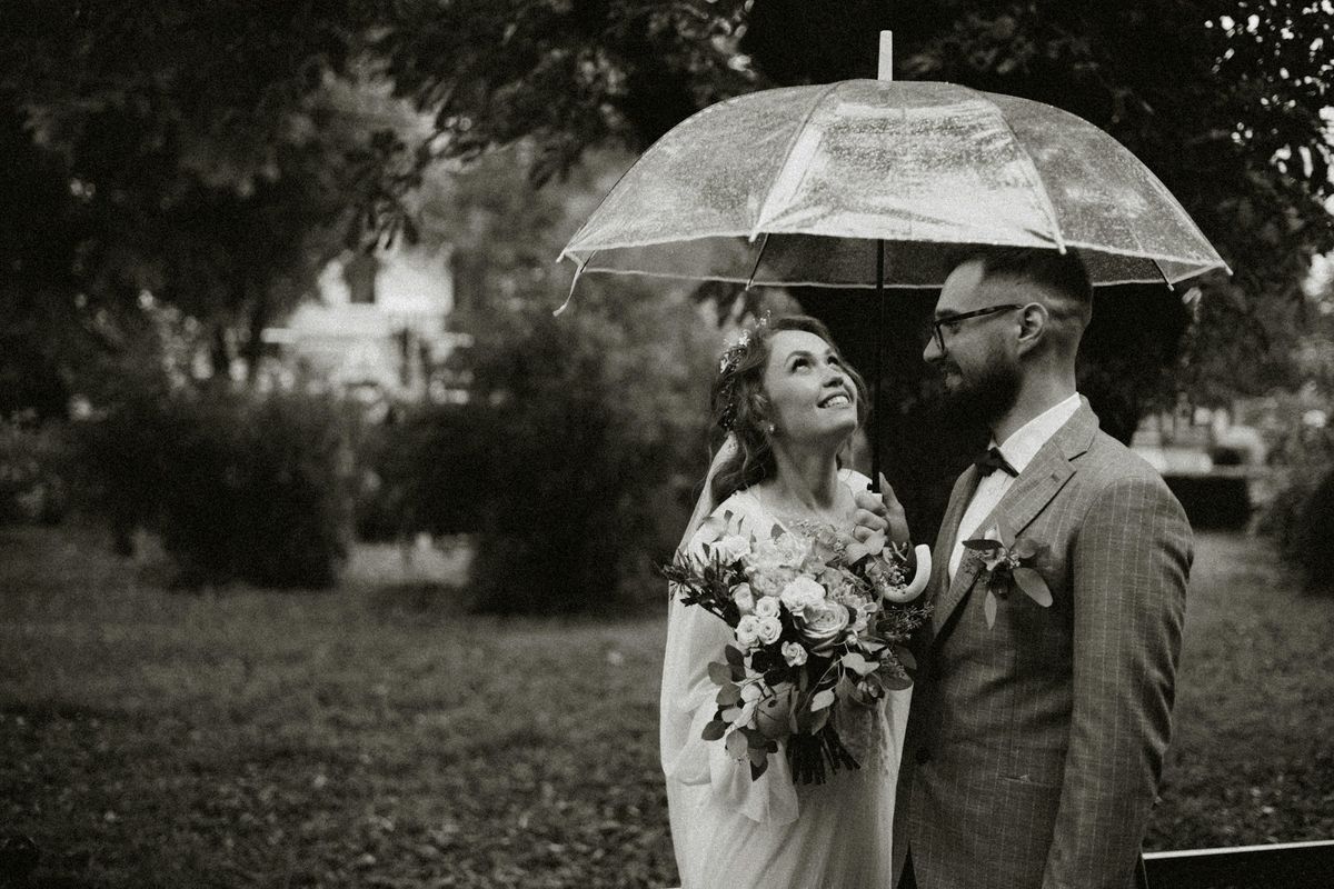 Bride and groom sharing a moment under a clear umbrella in the rain