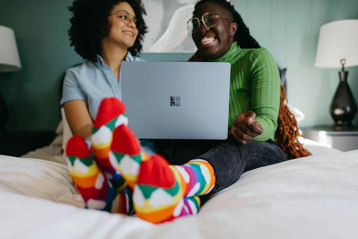 Couple laughing together while looking at a laptop on a bed