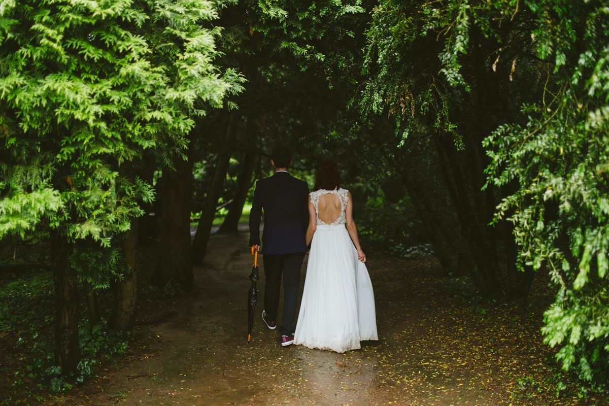 A bride and groom walking along a woodland path