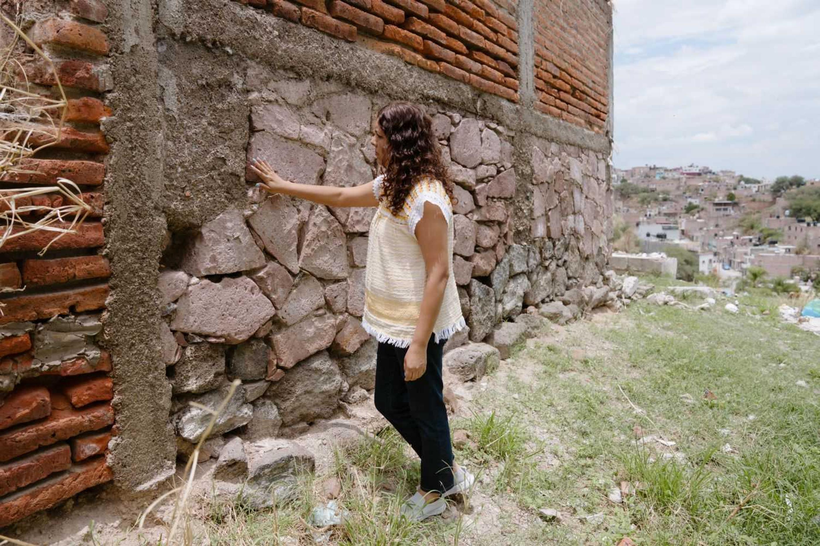 Beatriz touching a damaged building
