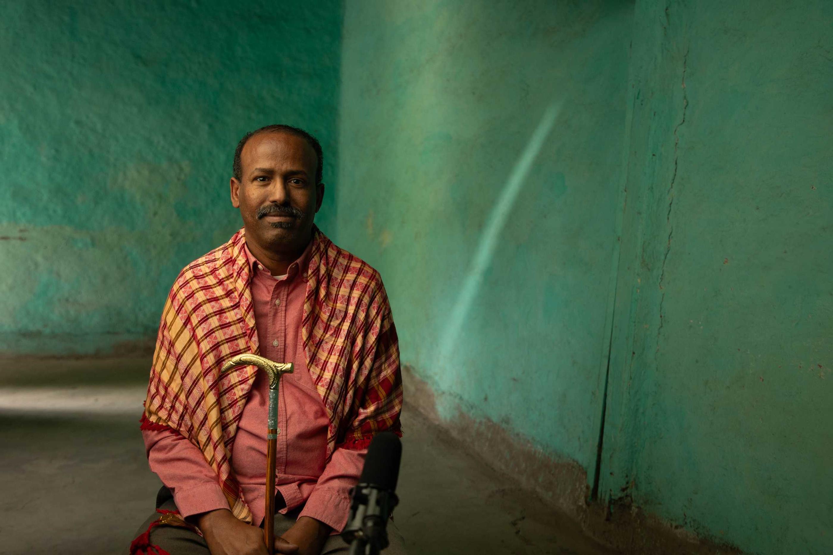 Aweis wearing his shawl holding his cane