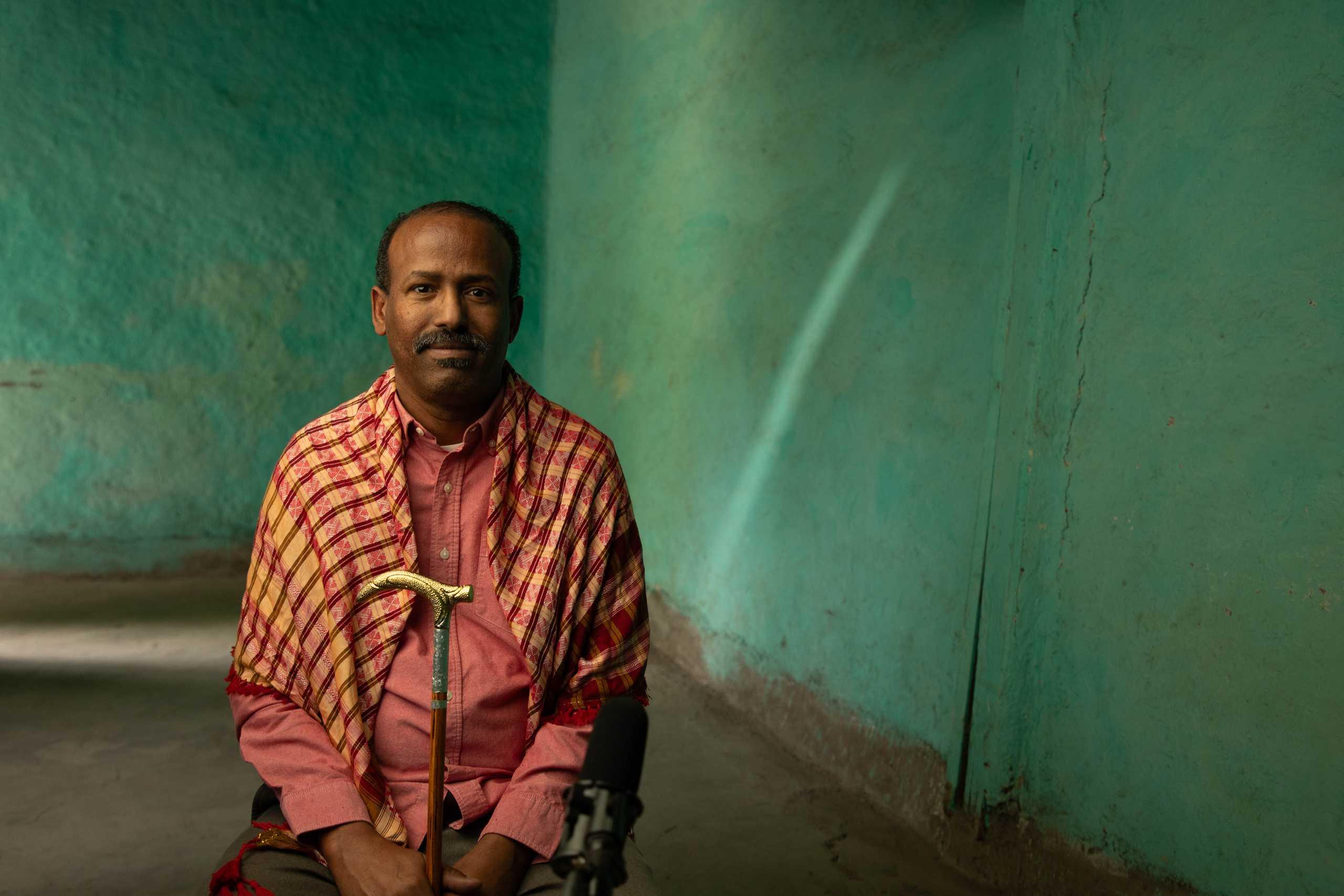 Aweis wearing his shawl holding his cane