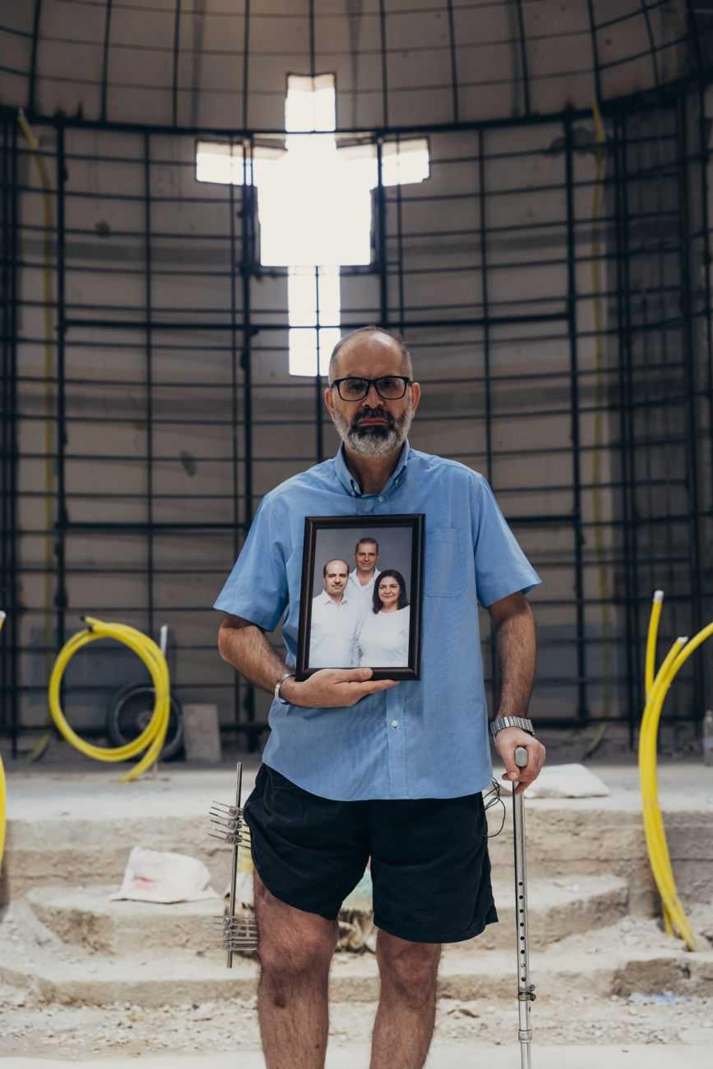 Elias holding a picture of his brother and sister who were killed in the attack