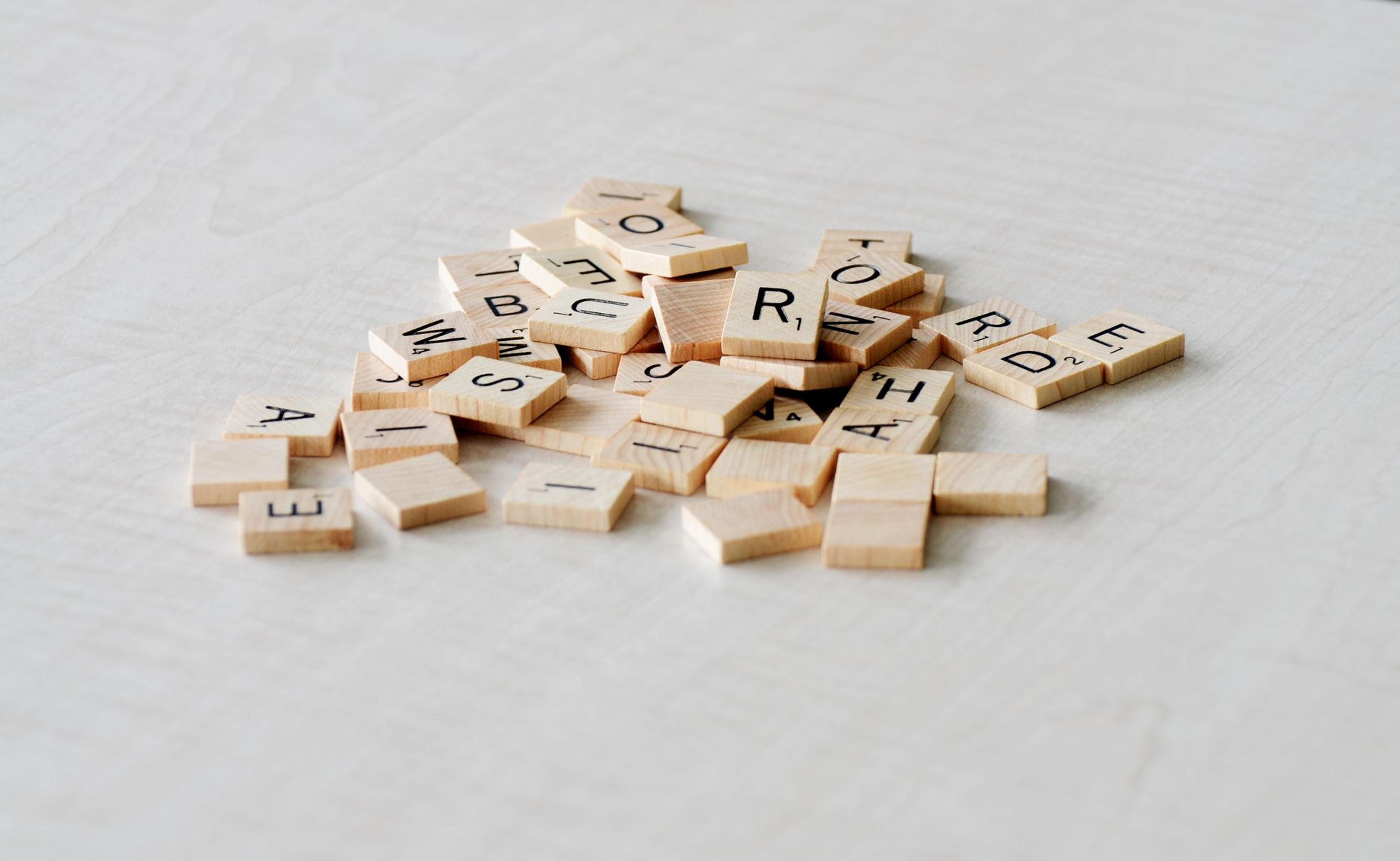 Close-up of wooden letter tiles scattered on a light table surface, ideal for word games.