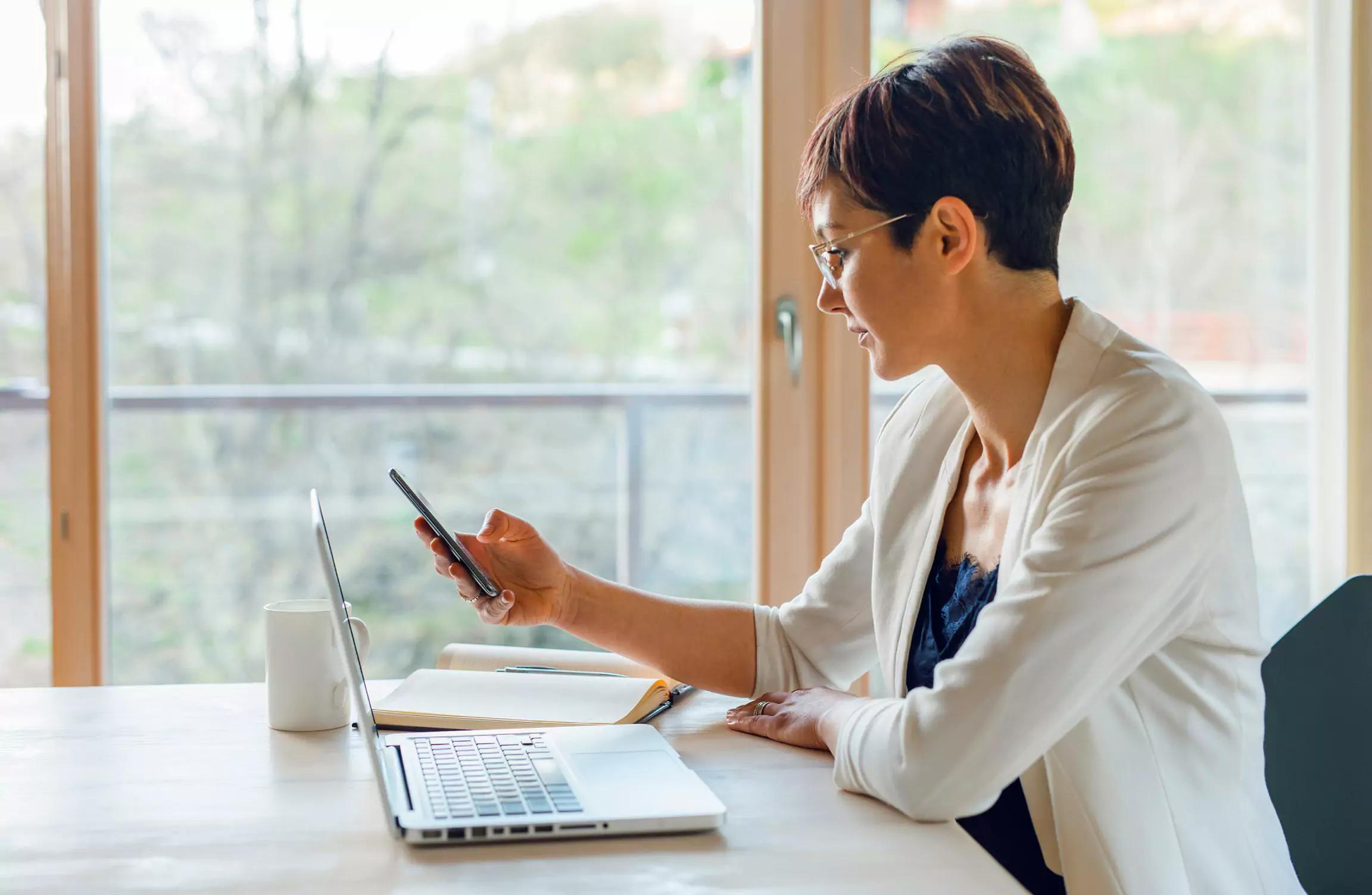 Woman working on phone and laptop